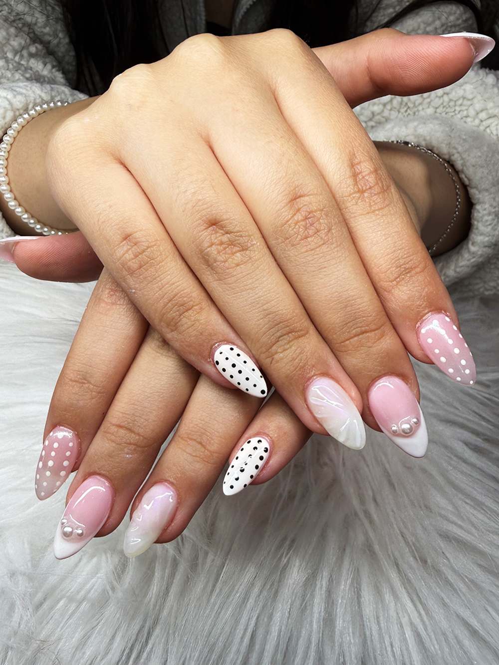 Soft pink almond nails with black and white polka dots, French tips and pearl accents by Chic Nail and Head Spa
